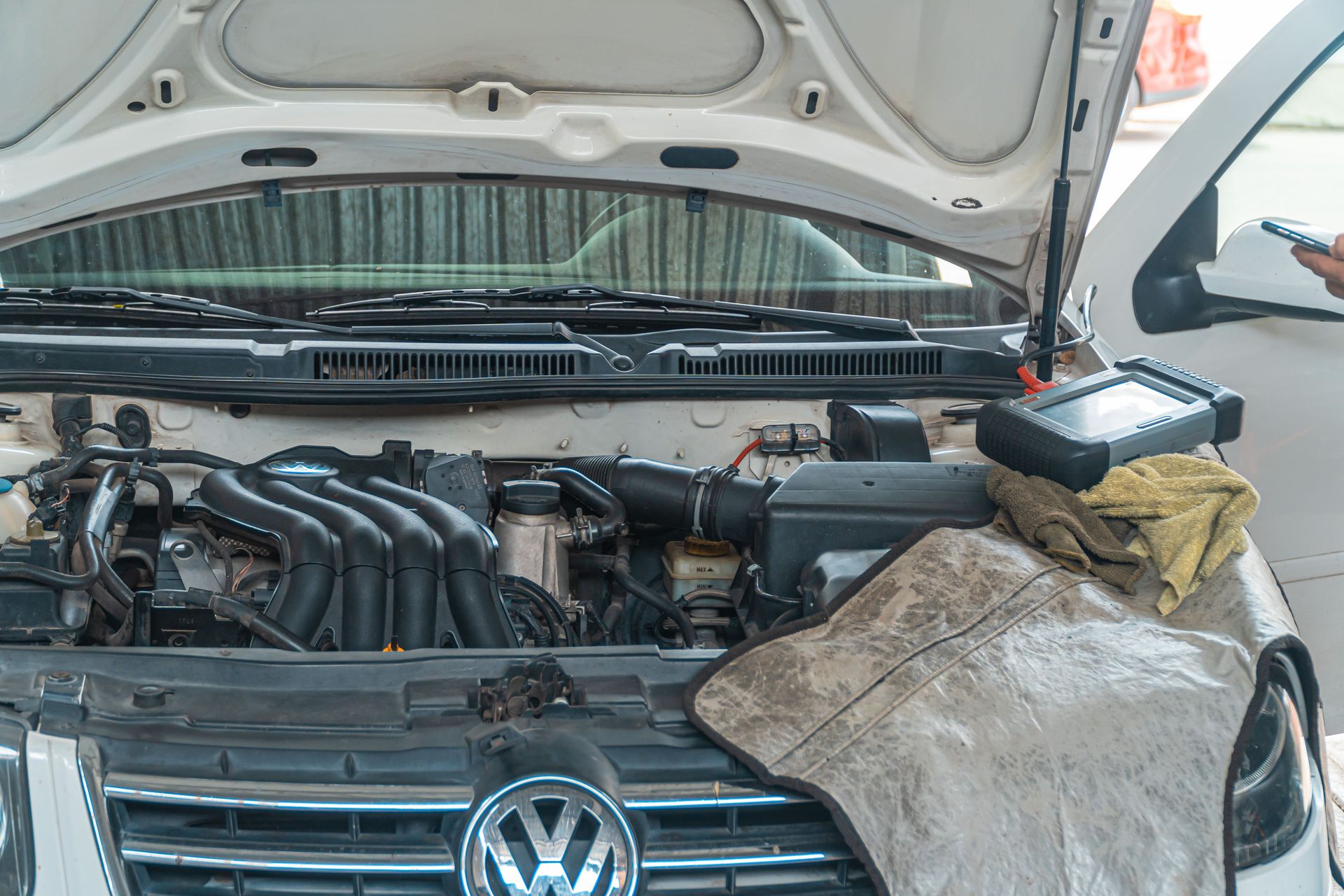 Close-up of a Volkswagen car engine undergoing repair in a garage, tools and diagnostic equipment in use.